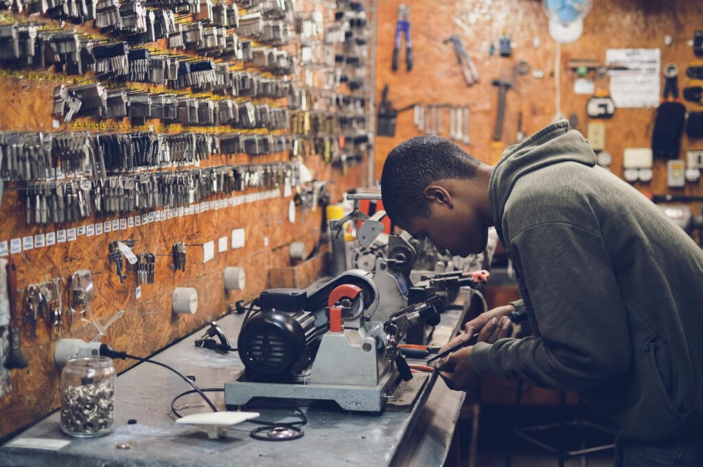 The Best Job Search Sites A focused craftsman works in a key-making workshop surrounded by tools and equipment.